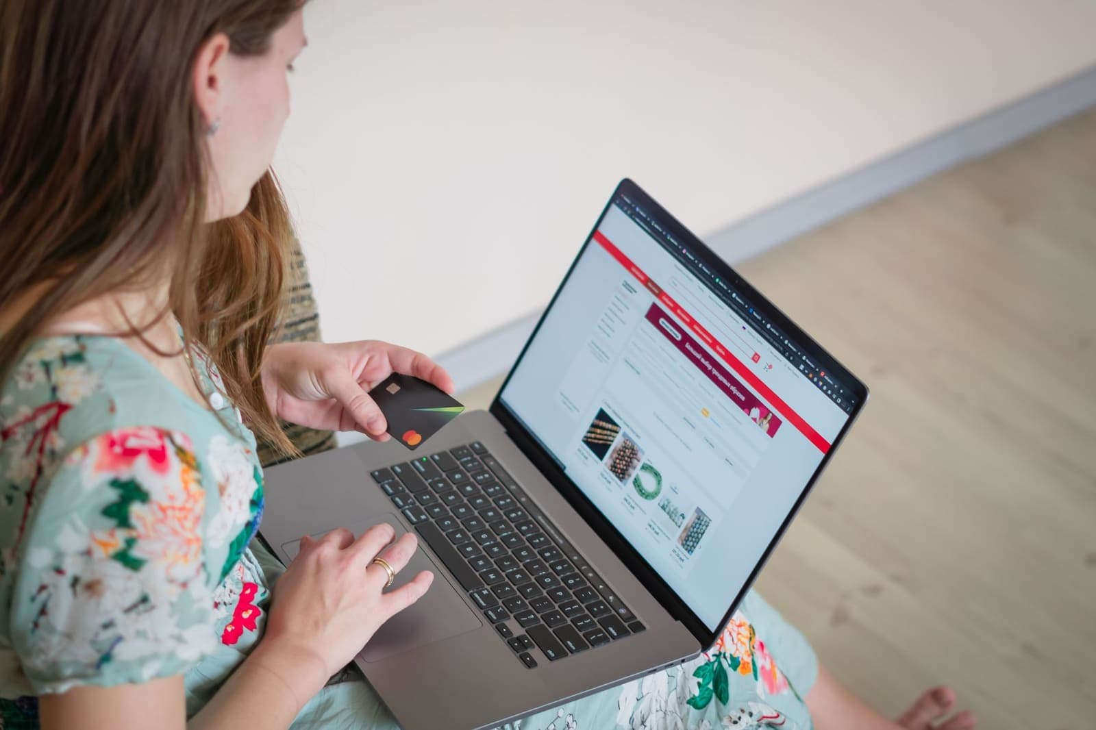Vrouw shopt online op haar laptop met een bankpas in haar hand
